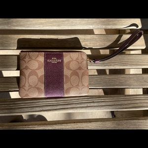 Small Coach wristlet with Coach logo and purple details.